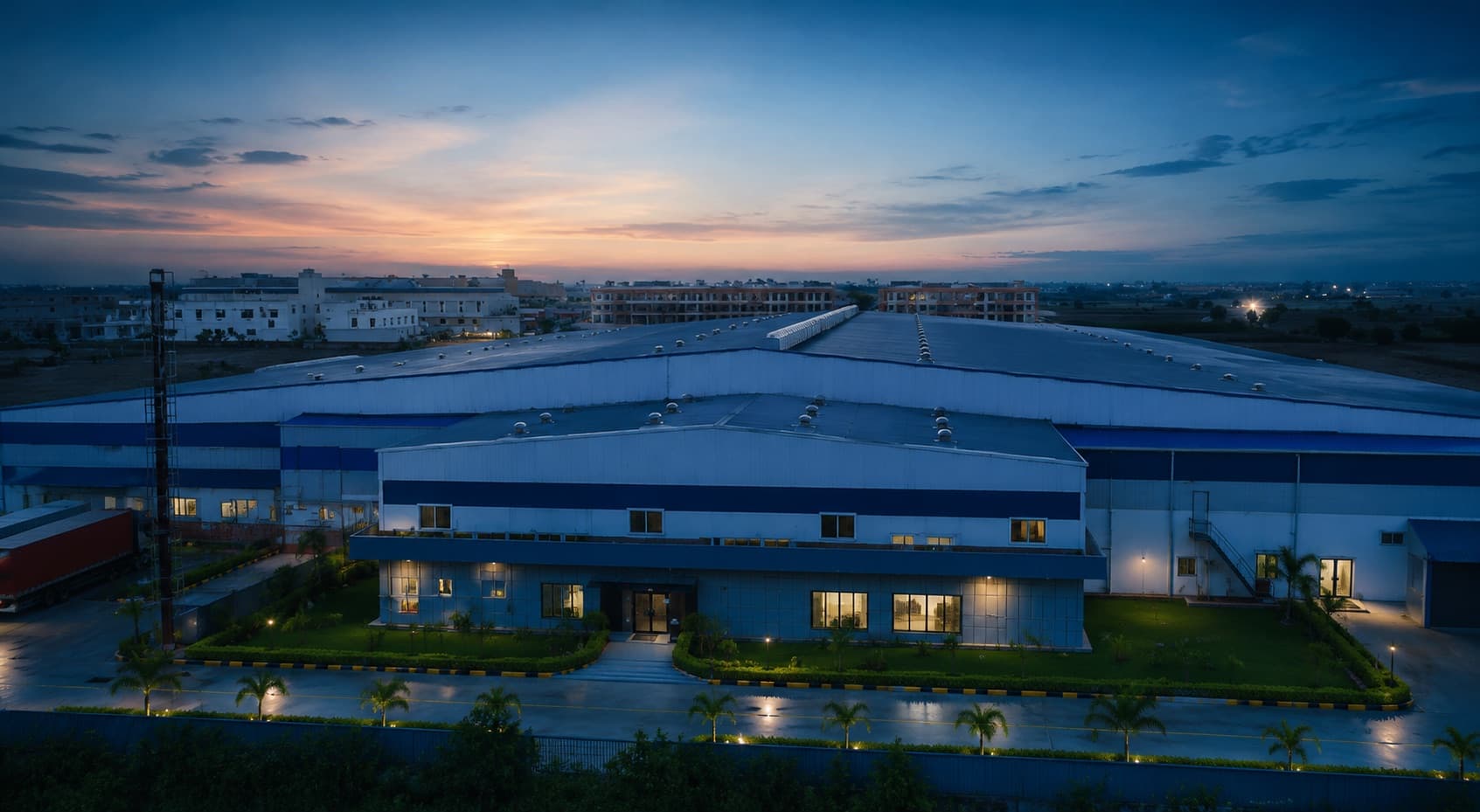 The Indus Appliances plant in Bahadurgarh at dusk, seen from above, its windows lit against the evening sky