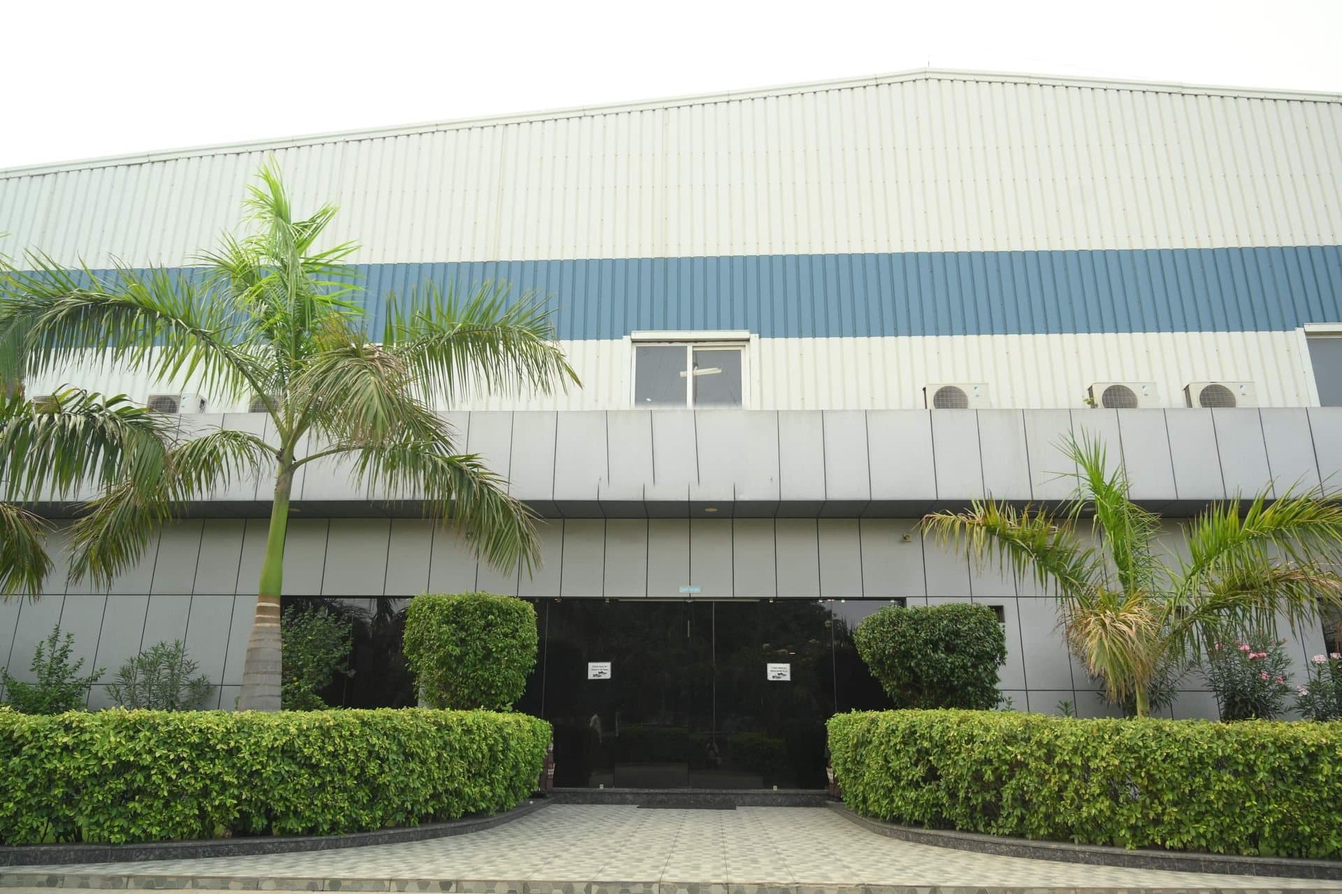The front entrance of the Indus Appliances plant in Bahadurgarh, with palms and hedges