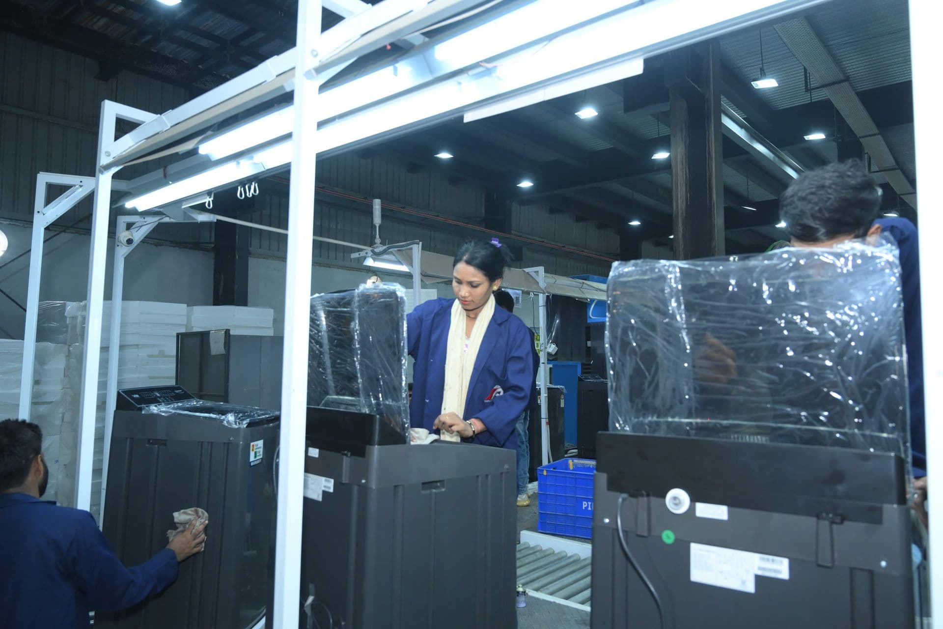 An operator on the washing machine assembly line, with finished units beside her